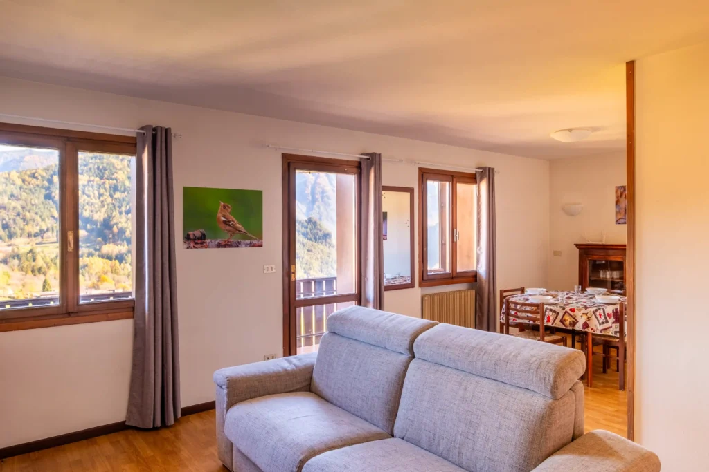 Spacious mountain-style living room with natural light and panoramic terrace access in Valle di Cadore.