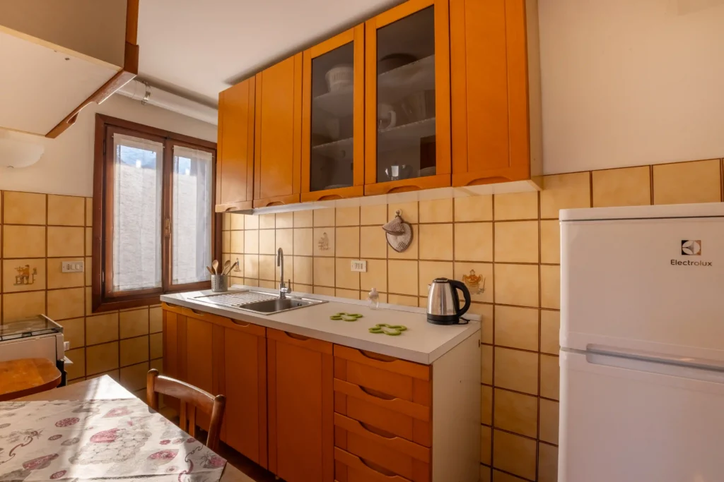 Fully equipped kitchen with fridge, oven, and mountain-view window — perfect for long stays in the Dolomites.