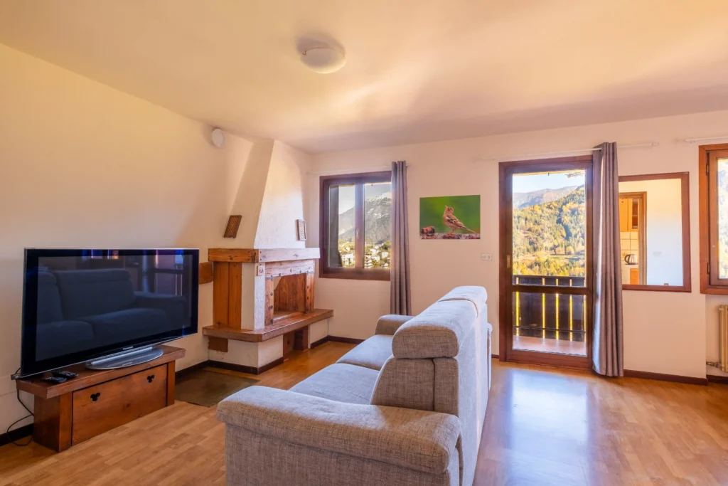 Bright living room of Mountain View Apartment with sofa, fireplace, and Dolomites view through large windows.